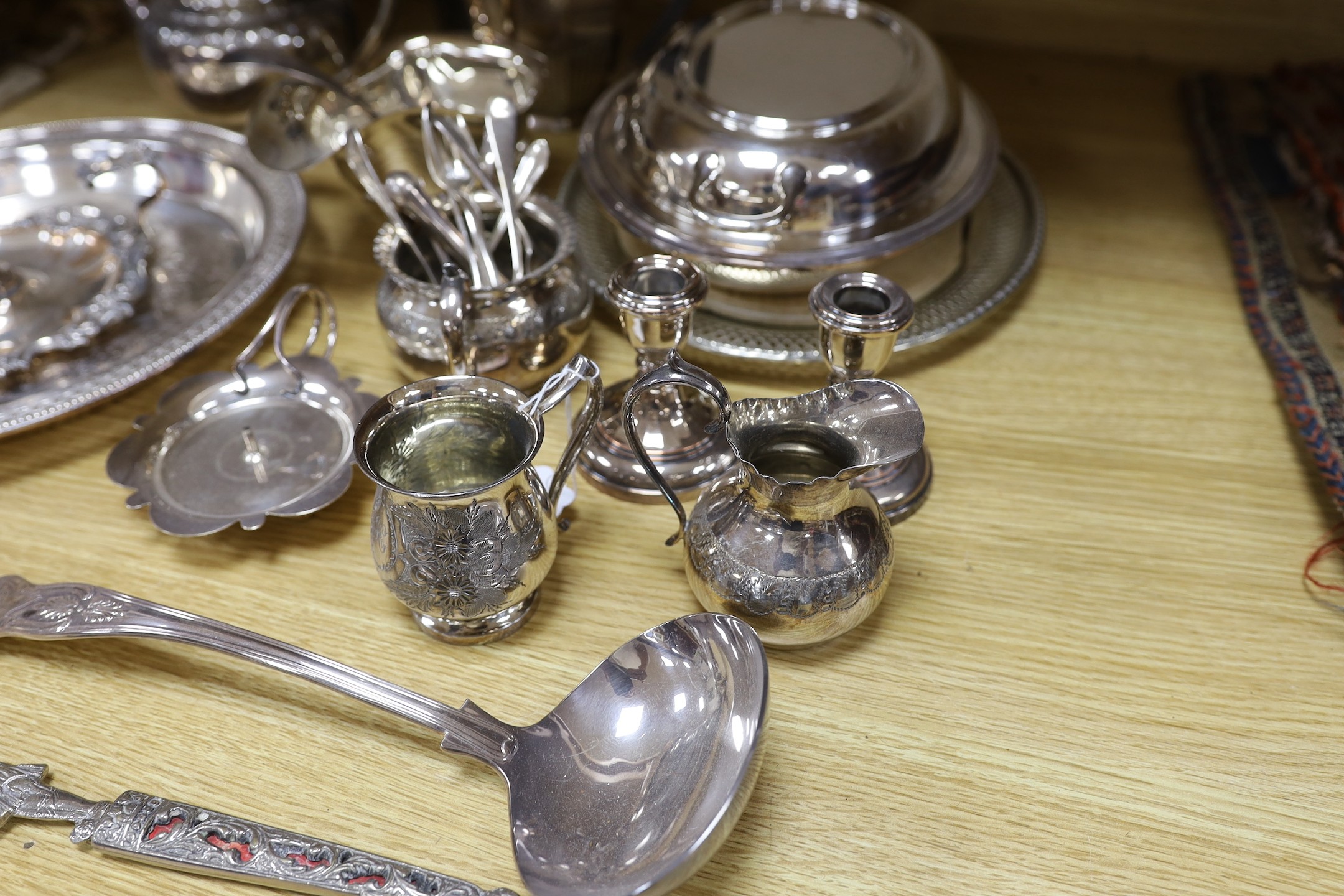 A quantity of assorted plated wares including a chamberstick, a tea set, flatware, a cocktail shaker, a sauceboat, goblets, etc.